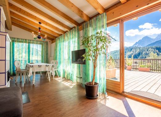 Suite Panorama con stufa in maiolica, lunga vetrata e terrazza con vista sulle Dolomiti.