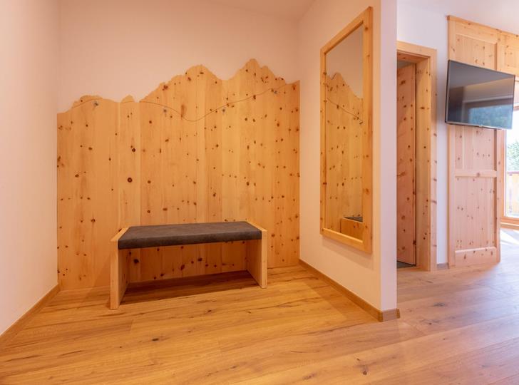 Heller Eingangsbereich mit Holzverkleidung, Sitzbank und Holzboden im Hotel Villa Stefania.