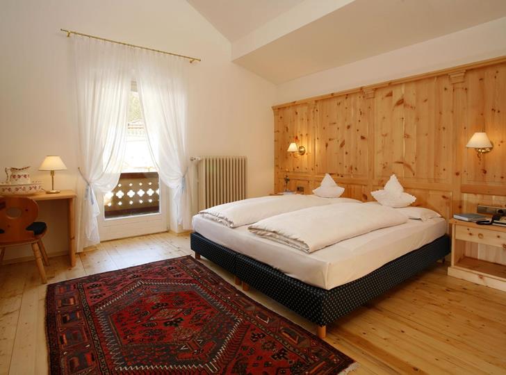 Luminosa camera doppia Superior di Villa Stefania con letto matrimoniale, zona salotto e mobili in legno.