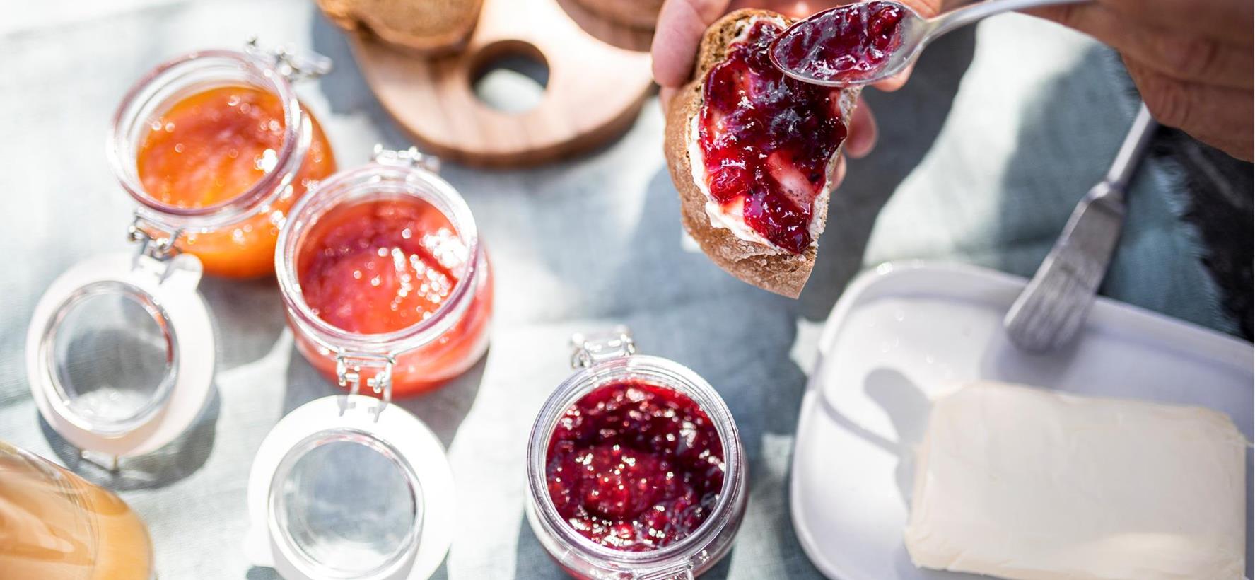Breakfast table set with various jams, bread and butter.