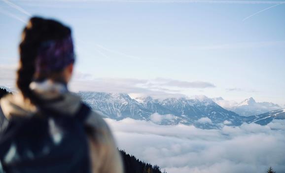Wanderer mit Blick auf eine Wolkendecke und die Berglandschaft der Dolomiten von einem Aussichtspunkt aus.