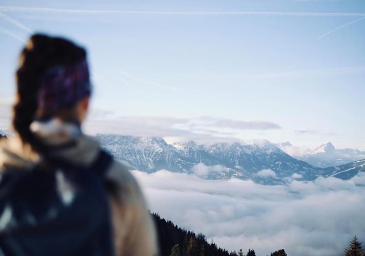 Wanderer mit Blick auf eine Wolkendecke und die Berglandschaft der Dolomiten von einem Aussichtspunkt aus.