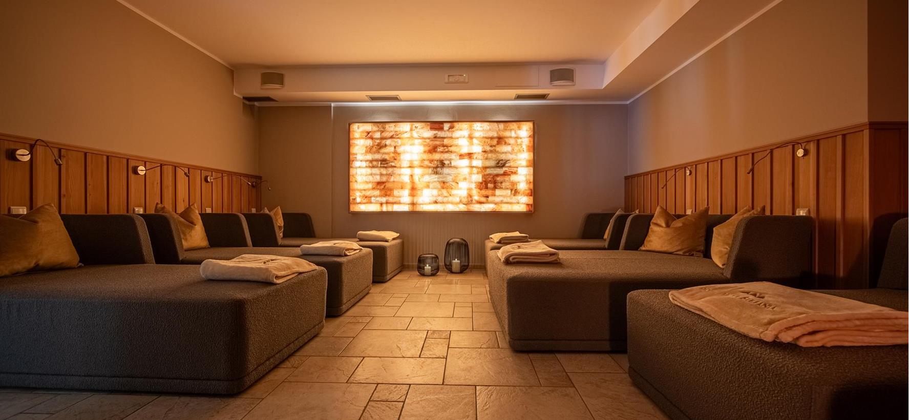 Sala relax nell’area wellness con grandi letti e luce soffusa.