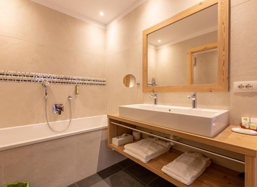 Badezimmer mit Badewanne und Doppelwaschbecken in der Suite Dolomiti.