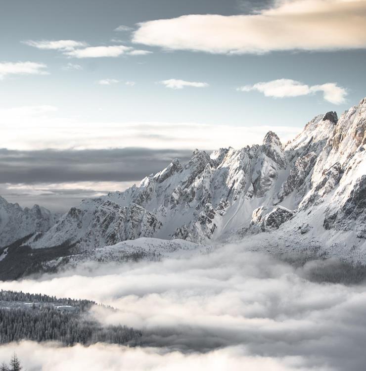 Die verschneiten Dolomiten mit aufziehendem Nebel über den Tälern.