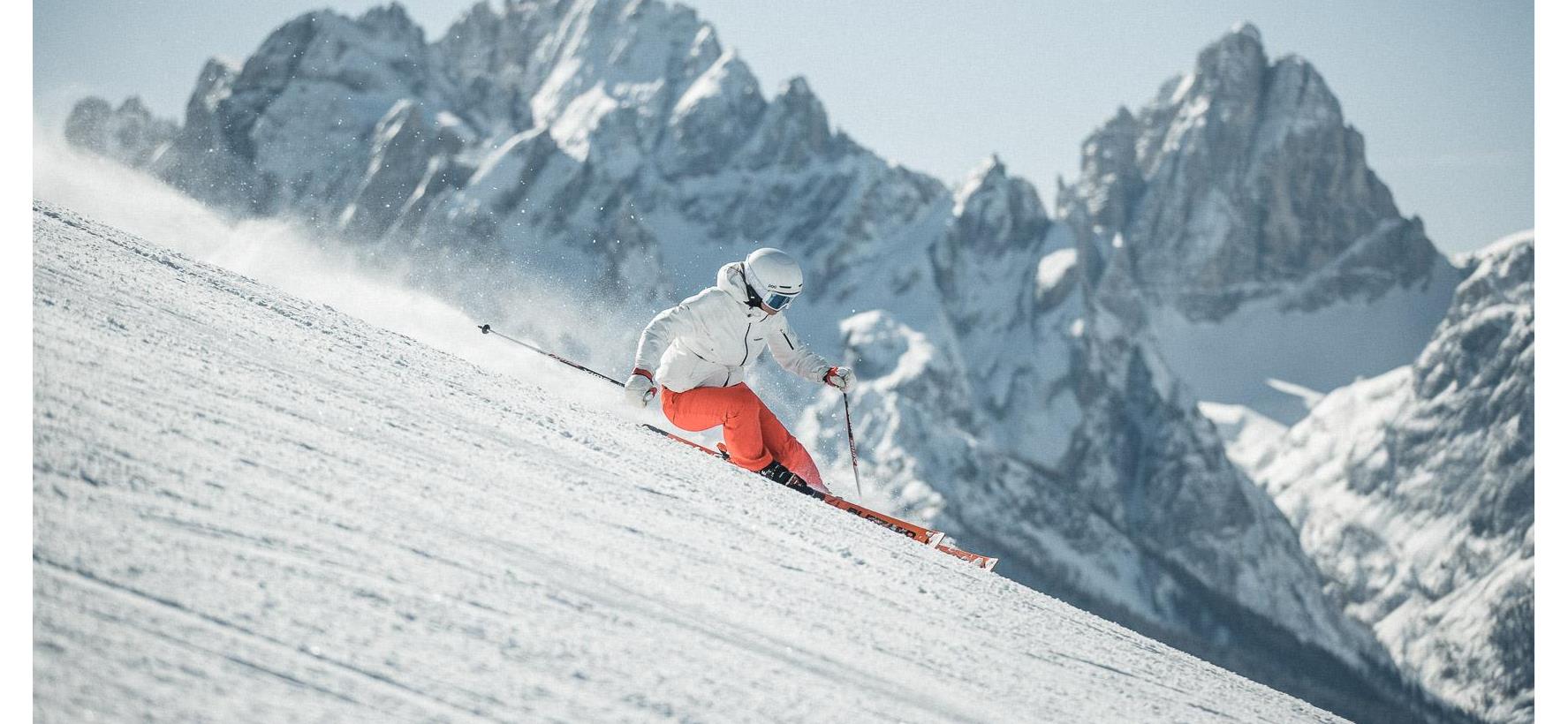 Ein Skifahrer auf der Piste mit den markantem Gebirge der Dolomiten im Hintergrund.