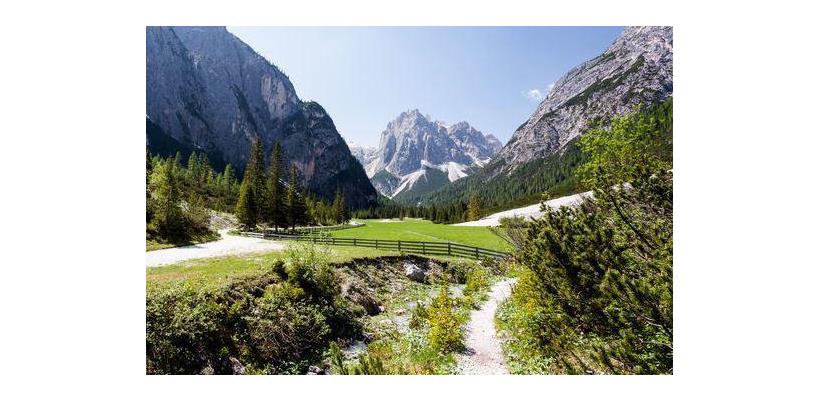 Wanderweg durch das Innerfeldtal mit Bachlauf, grünen Almwiesen und Dolomitengipfeln im Hintergrund.
