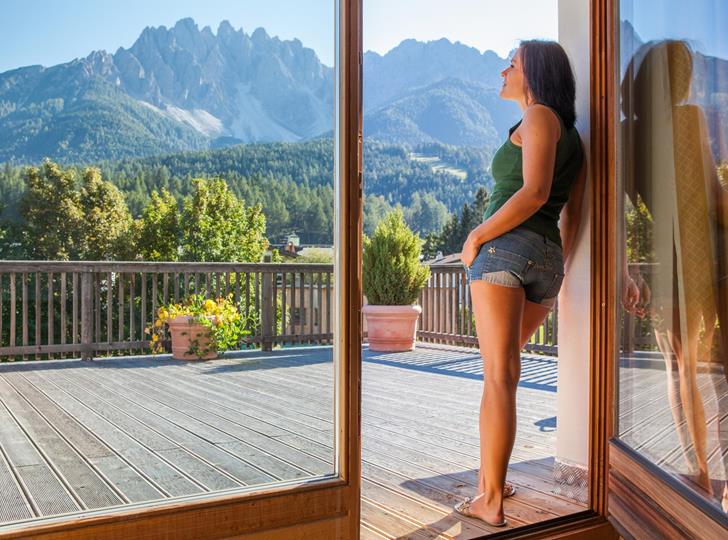 Frau auf der Terrasse einer Junior Suite im Hotel Villa Stefania mit Blick auf die Dolomiten.