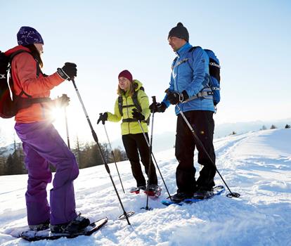 Snowshoe hikers standing in a snow-covered mountain landscape.