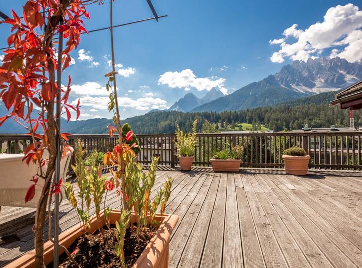 Terrasse Suite Panorama mit herbstlichen Pflanzen und Blick auf die umliegenden Dolomiten im Sonnenschein.