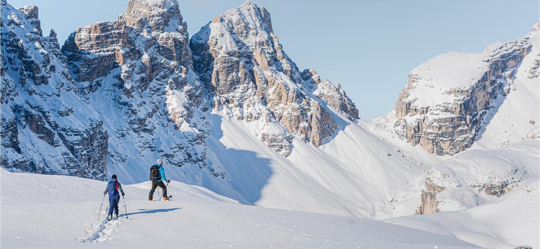 Snowshoe hikers in a snow-covered landscape in the Tre Cime di Lavaredo area of the Dolomites.