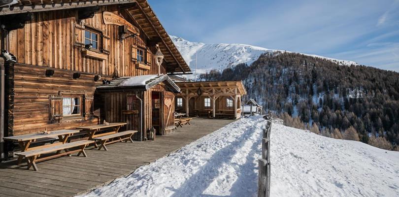 Klammbachalm mountain hut in a snow-covered winter landscape, surrounded by the Dolomites.