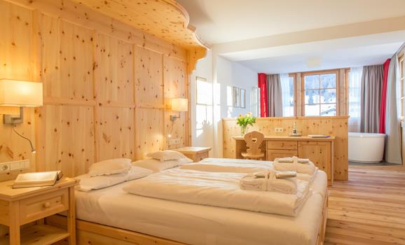 Romantic Suite con letto matrimoniale, rivestimento in legno e accogliente angolo soggiorno.