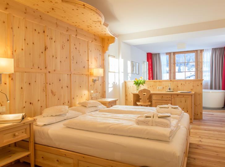 Romantic Suite mit Doppelbett, Holzvertäfelung und gemütlicher Sitzecke.