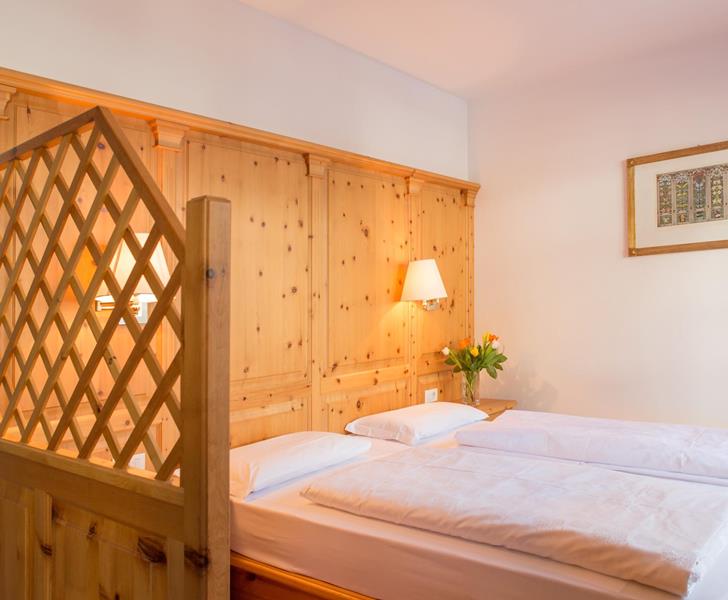 Camera Superior con letto matrimoniale, rivestimento in legno chiaro e parete divisoria in legno.