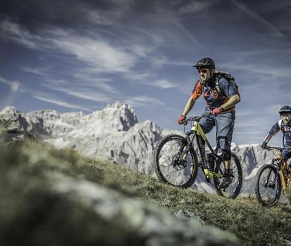 Due mountain biker su un sentiero attraverso il paesaggio montano estivo delle Dolomiti