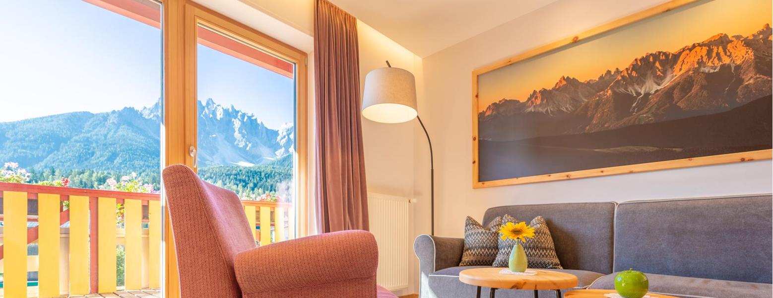 Helle Suite Dolomiti der Villa Stefania mit gemütlichem Wohnbereich und großen Panoramafenstern mit Blick auf die Dolomiten.