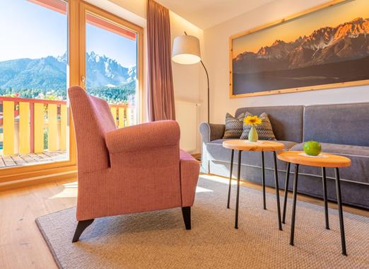 Helle Suite Dolomiti der Villa Stefania mit gemütlichem Wohnbereich und großen Panoramafenstern mit Blick auf die Dolomiten.