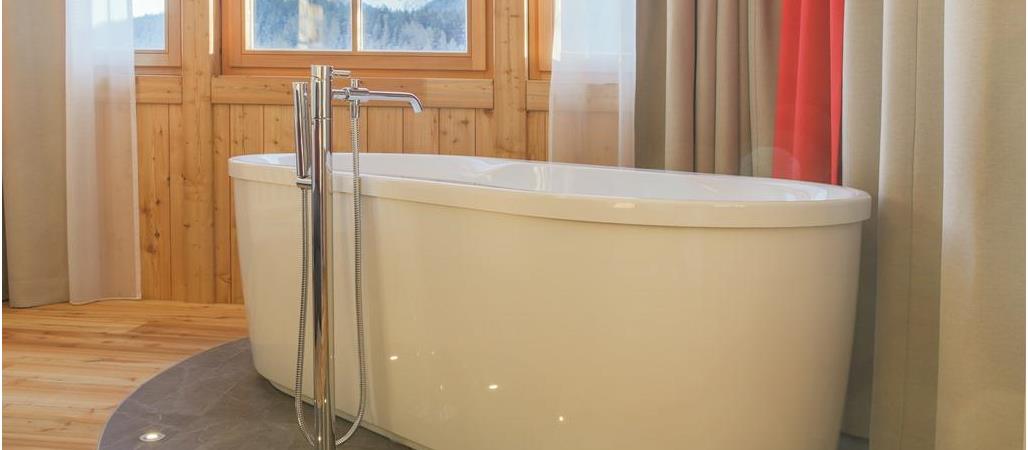 Badewanne in der Romantic Suite mit Fenster und Blick auf die umliegenden Dolomiten.