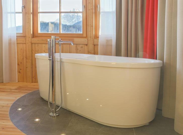 Badewanne in der Romantic Suite mit Fenster und Blick auf die umliegenden Dolomiten.