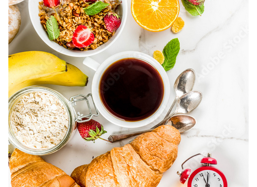 Breakfast table set with coffee, fresh fruit, muesli and croissants.