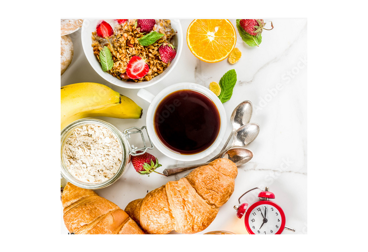 Breakfast table set with coffee, fresh fruit, muesli and croissants.