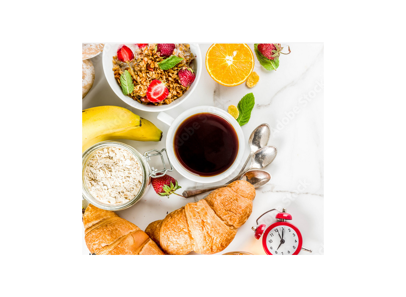 Gedeckter Frühstückstisch mit Kaffee, frischem Obst, Müsli und Croissants.