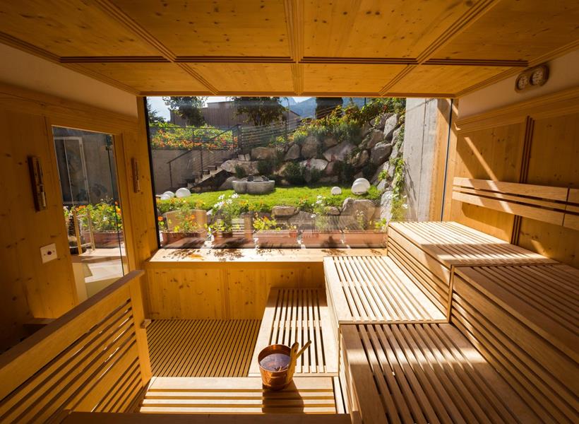 Sauna panoramica di Villa Stefania con ampia vetrata e vista sul giardino e sul paesaggio montano circostante.