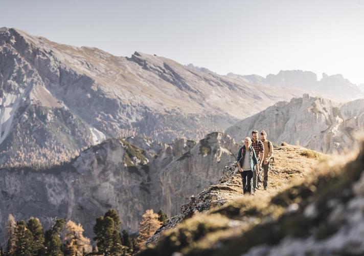 Wanderer in herbstlicher Landschaft mit markantem Gebirge im Hintergrund.