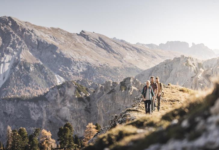 Wanderer in herbstlicher Landschaft mit markantem Gebirge im Hintergrund.