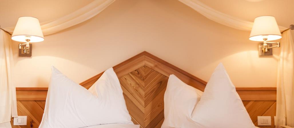 Camera Superior con letto matrimoniale, rivestimento in legno e due lampade da comodino.