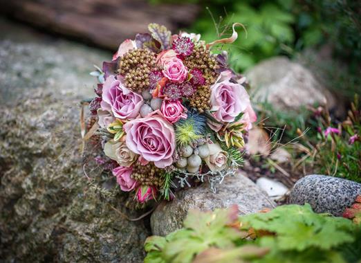 Mazzo di fiori con rose rosa su una pietra in un ambiente naturale.