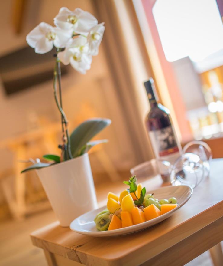 Tisch in der Suite Natura mit Obstteller, Wein, Weigläsern und einer Orchidee.