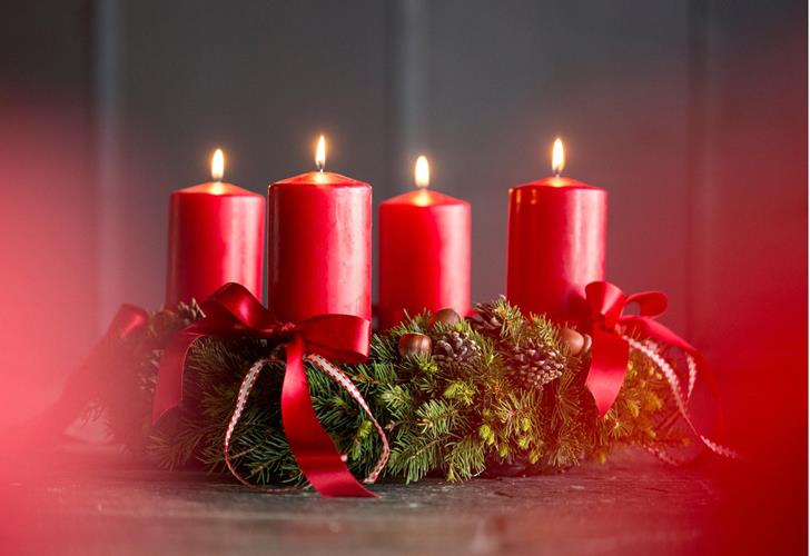 Adventkranz mit roten Kerzen und Schleifen.