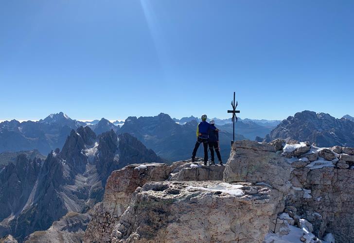 Due arrampicatori si trovano sulla cima di una montagna e ammirano il suggestivo paesaggio montano circostante.