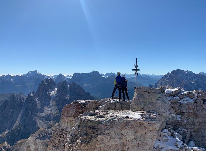 Zwei Kletterer stehen auf einem Gipfel und schauen in die markante Bergwelt ringsum.