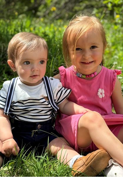 Die Kinder Paul und Carolina sitzen auf einer Wiese.