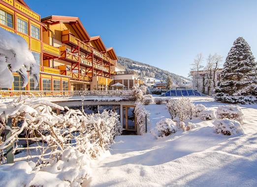 Vista esterna di Villa Stefania in un paesaggio invernale innevato, con giardino e alberi coperti di neve e cielo azzurro.