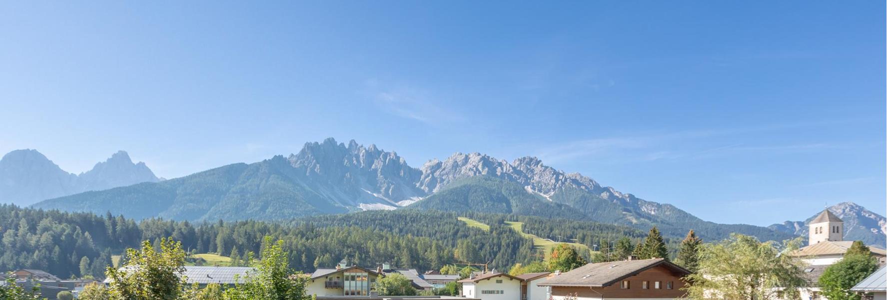 Vista sul giardino di Villa Stefania con prato prendisole, lettini e le Dolomiti sullo sfondo.