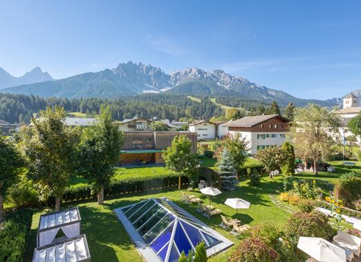Blick auf den Garten der Villa Stefania mit Liegewiese, Sonnenliegen und den Dolomiten im Hintergrund.