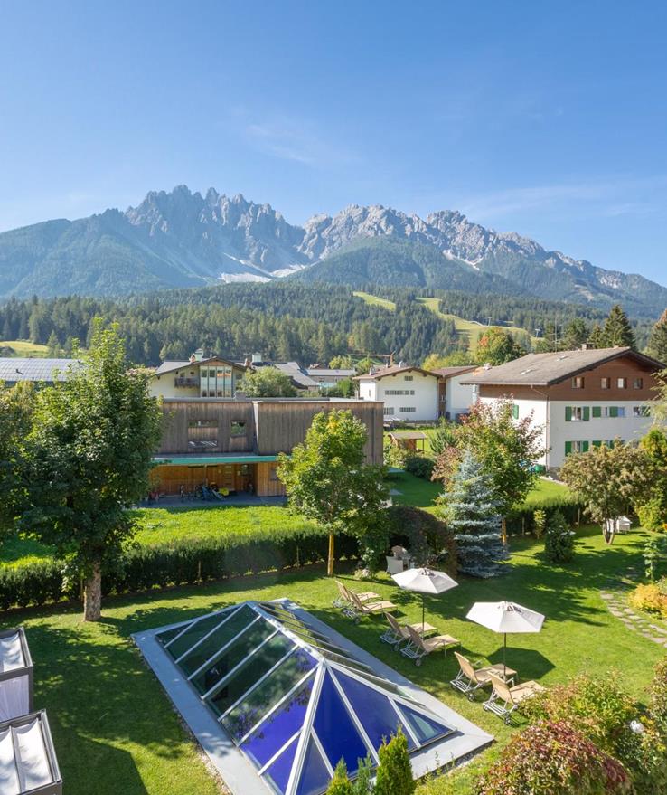 Vista sul giardino di Villa Stefania con prato prendisole, lettini e le Dolomiti sullo sfondo.