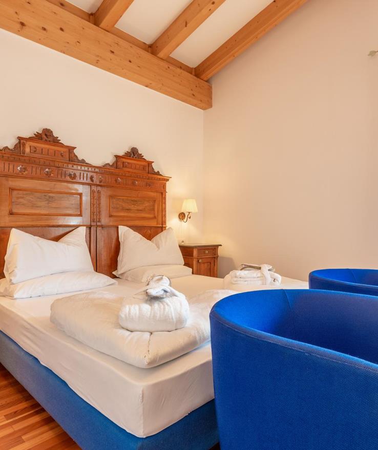 Bright Suite Panorama with a double bed, blue armchairs and exposed wooden ceiling beams.
