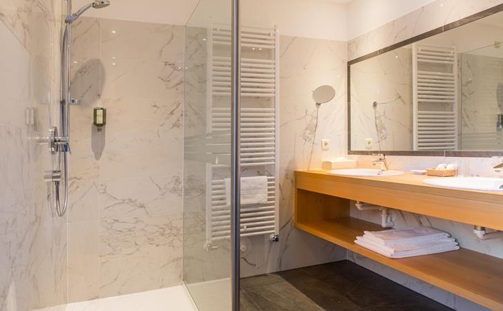 Romantic Suite bathroom with walk-in shower, large mirror and washbasin.