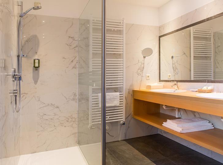 Bagno della Romantic Suite con doccia walk-in, grande specchio e lavabo.