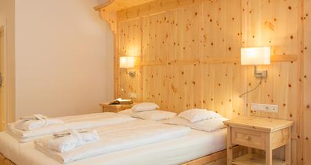 Schlafzimmer Romantic Suite mit großem Doppelbett und heller Holzvertäfelung.