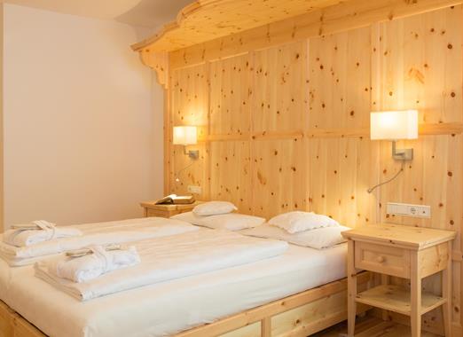 Bedroom of the Romantic Suite with large double bed and light wood panelling.