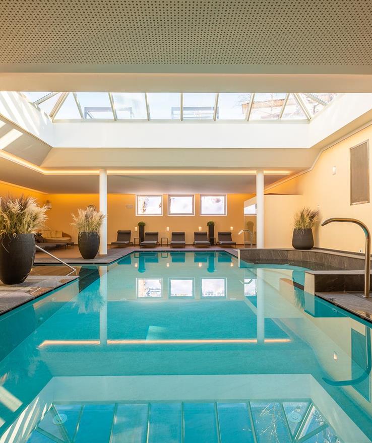 Innenpool der Villa Stefanie mit Sonnenliegen und großem Dachfenster.