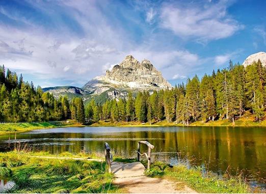 Lake Antorno in the Dolomites with calm water, surrounded by forests and impressive mountain peaks in the background.