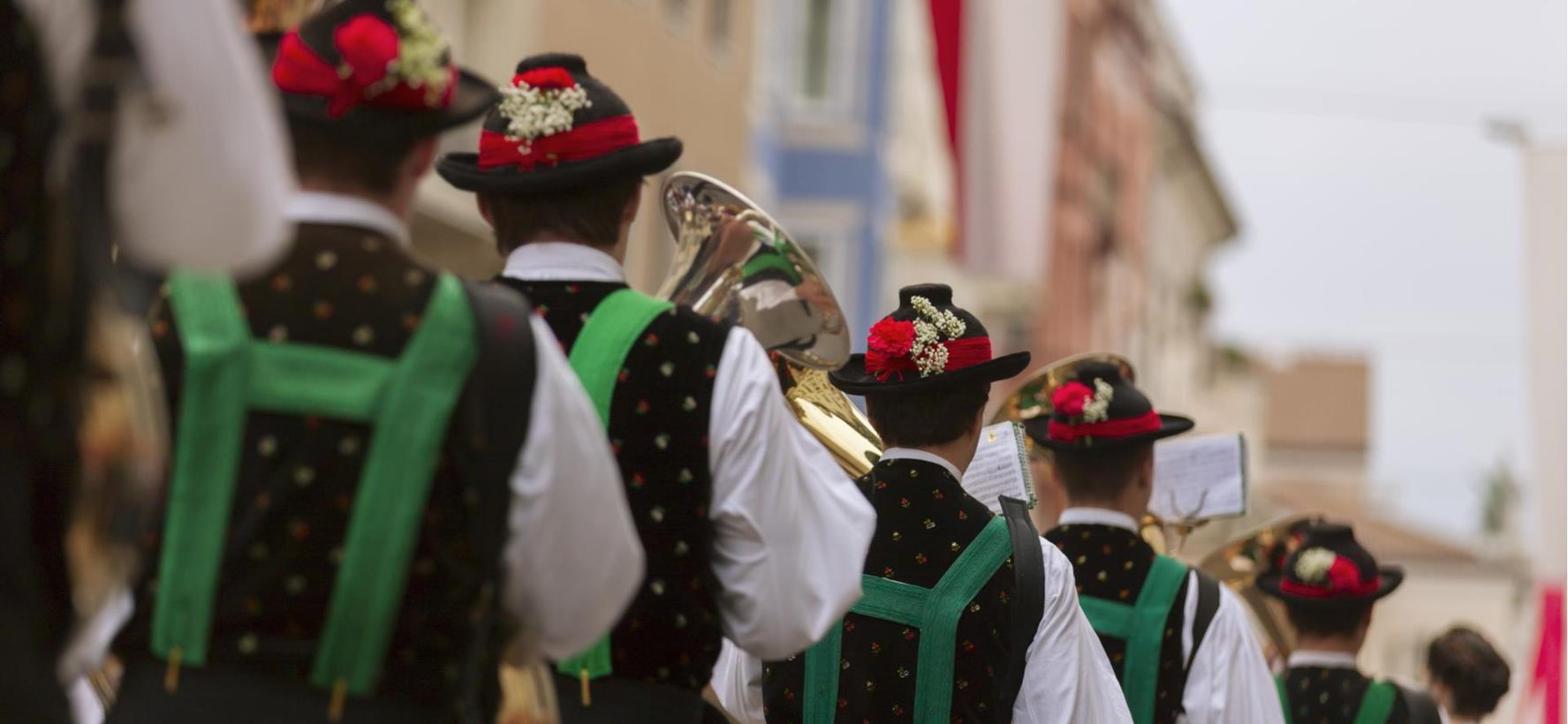 Nahaufnahme von Musikern einer Musikkapelle bei einem Umzug durch eine Ortschaft.