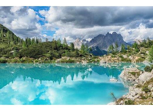 Türkisblauer Sorapissee in den Dolomiten mit spiegelndem Wasser, imposanten Felswänden und alpiner Berglandschaft im Hintergrund.